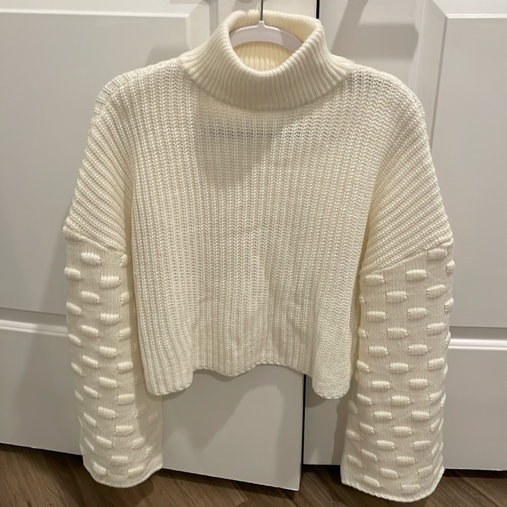 Crop sweater with knit design on sleeves.